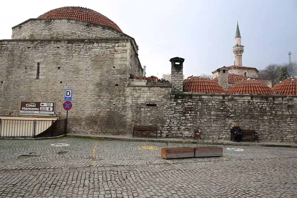 Cinci Hamamı’nın taş cephesi, arkada kubbeler ve cami minaresi