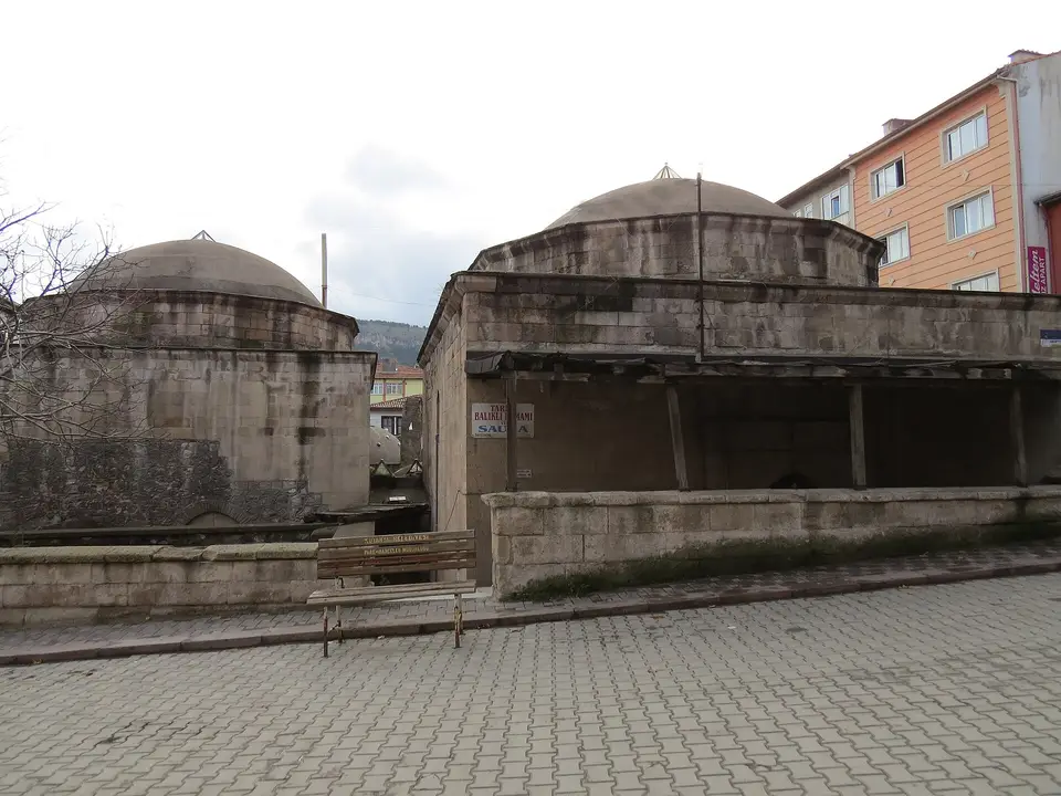 Kütahya’da Balıklı Hamamı’nın kubbeleri ve taş gövdesi, önünde Arnavut kaldırımlı sokak