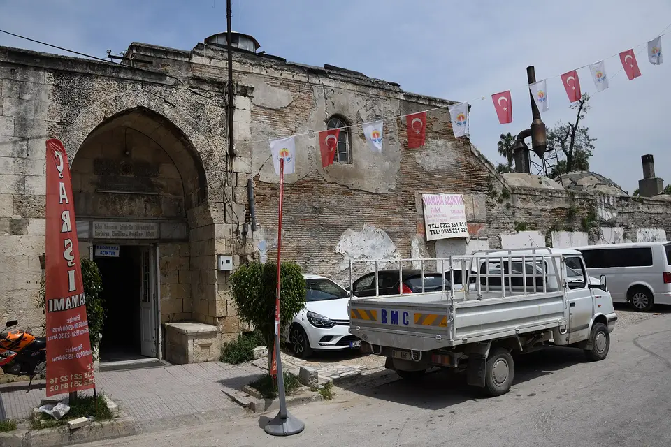 Adana’da Çarşı Hamamı’nın sivri kemerli taş girişi, kapının yanında “Çarşı Hamamı” tabelası