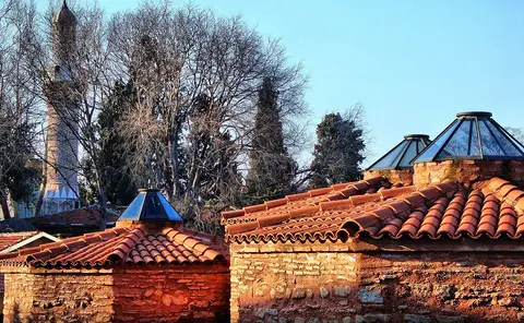Bursa’da Umurbey Hamamı’nın kiremit kaplı kubbeleri ve camlı fenerleri, arkada minare